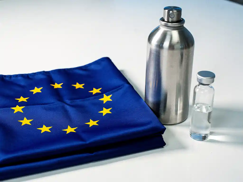 EU flag beside a nitrogen canister and glass vial on a white lab surface, representing chemical regulation and environmental compliance.