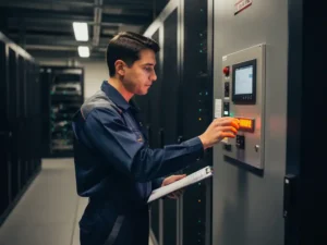 Fire safety technician inspecting a wall-mounted suppression system panel in a server room, clipboard in hand during compliance check.