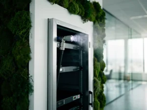 Fire suppression nozzle inside a server cabinet surrounded by green moss on white walls, with nitrogen mist in a LEED-certified data center interior.